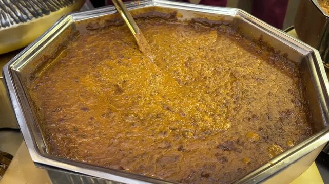 Slow-cooked Dal Makhani enriched with butter and cream, served in a traditional catering vessel at a grand wedding banquet in India.