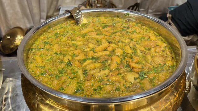 A vibrant serving of Sev ki Sabji (spiced gram flour noodles in a tangy tomato-yogurt gravy) at a traditional Indian wedding banquet, showcasing regional Marwari culinary heritage.