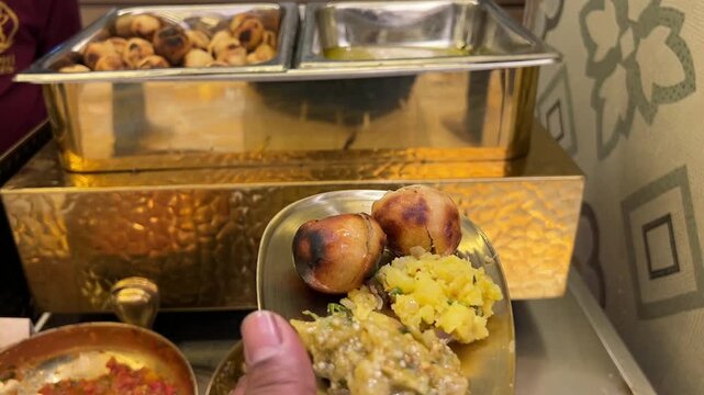 Traditional Litti Chokha with ghee served in golden utensils; a popular regional Indian dish presented in luxury brassware during a wedding celebration in India.