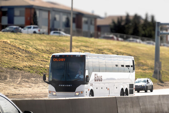 Calgary, Alberta, Canada. April 30, 2026. White Ebus coach traveling on a highway toward Calgary with a driver visible behind the wheel.