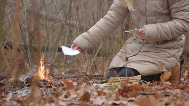 Woman burning documents with flames, turning paper into ashes Symbolic farewell and emotional release. Destruction of sensitive information in isolation. Solitary reflection and transformative ritual.