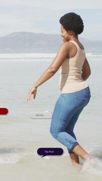 Vertical video: Foot stepping into surf initiating social overlays, woman wading and sharing moment