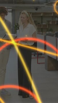Vertical video: Office staff pointing tablet causing tapping, checking info as neon rings sweeping