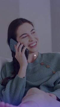 Vertical video: Woman on couch on phone, laughing while call producing sparkles for social content