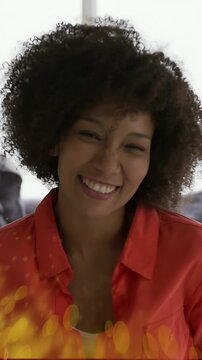 Vertical video: Woman in red smiling to laughing as golden particles entering sweeping chest, ads