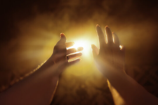 Hands Reaching Up into Bright Light
