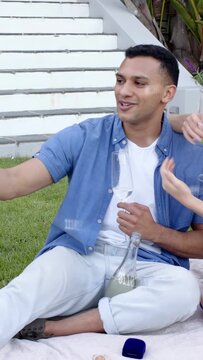 Vertical video: Couple reaching phone and toasting on blanket, binary overlay on phone for social
