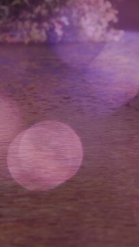 Vertical video: Water rippling, pink bokeh drifting while focus shift causing fading reflections