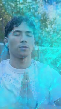 Vertical video: Man lifting hands to prayer in garden causing blue overlay wrapping face for health