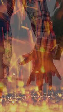 Vertical video: Two women lowering hands in film, linking fingers showing bond under flame overlay