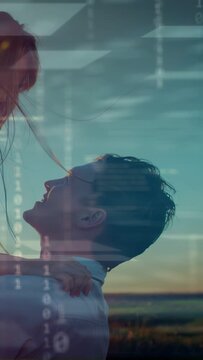 Vertical video: Man reaching, lifting woman for playful hug at sunset field, tech overlaying couple