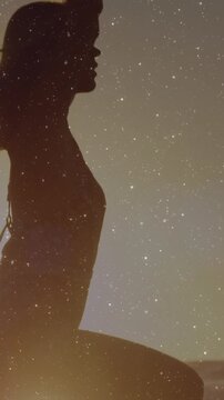 Vertical video: Woman balancing on board at sunset foot plant causing rising under grain for health
