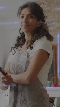 Vertical video: Artist facing lens picking brushes and smiling, showing craft with light streaks