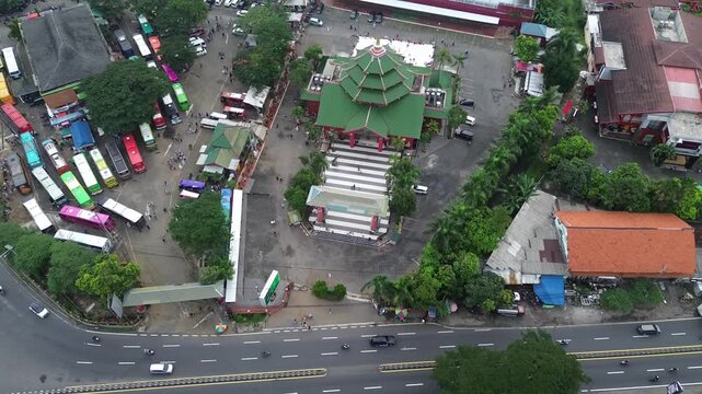 Drone view of a landmark mosque with green roof and bus terminal
