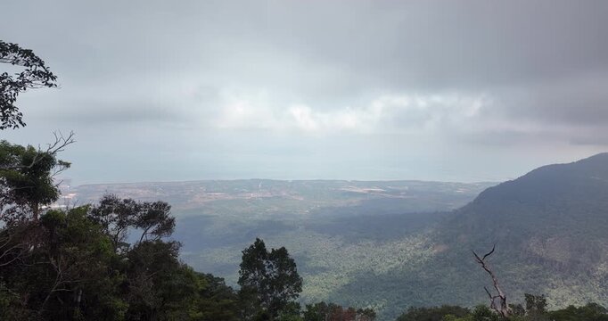 Panoramic view from the summit of Bokor Mountain overlooking the Kampot coastline under a misty, cloudy sky.