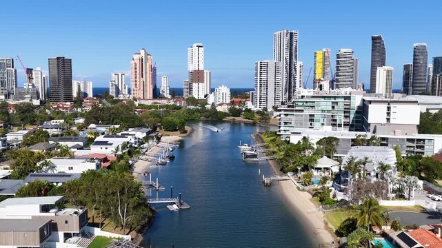 Aerial view of a jetski navigating the canals of broadbeach on Australia's Gold Coast, modern high-rise city skyline in background.