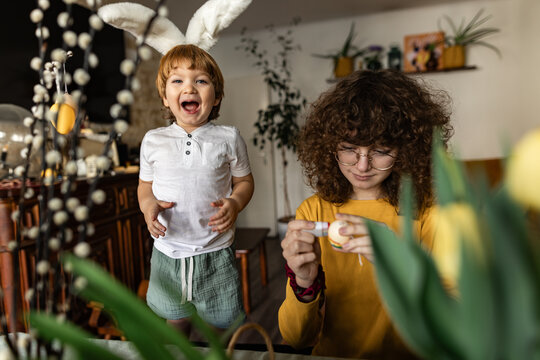 Brother and sister decorating Easter egg at home
