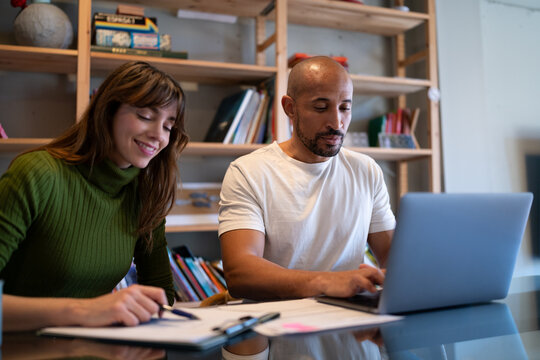 Couple signing contract at home together at a table with a laptop