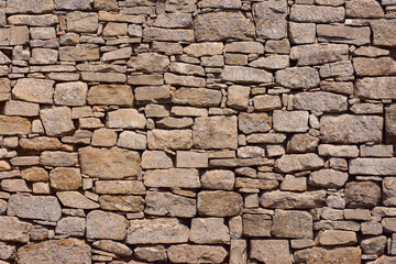 Fototapeta premium Close up of old rustic stone wall with irregular natural rocks. Weathered masonry texture background for architecture, construction or design use.