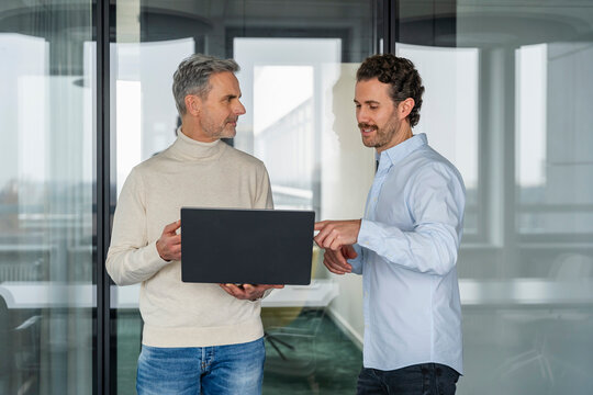 Two men discussing business with a laptop in a modern office