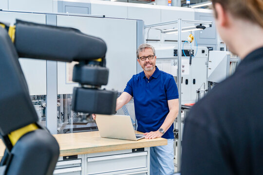 Engineer meeting with employee and industrial robot in factory
