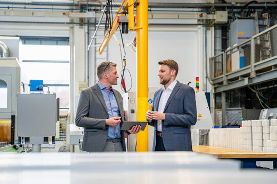 Manager talking with engineer in factory using tablet