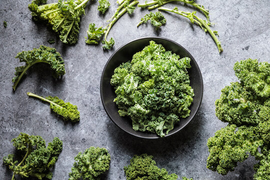 Fresh cleaned kale in a black bowl on a dark countertop
