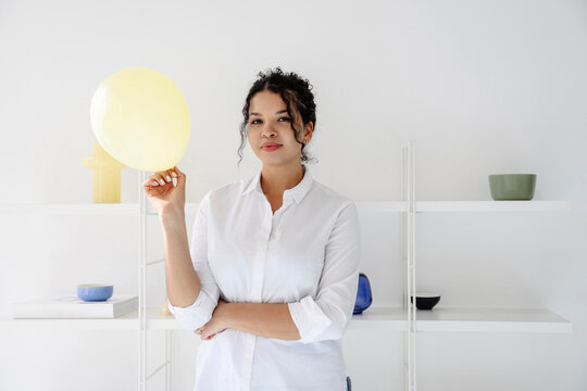 Woman holding a yellow balloon in a modern white room
