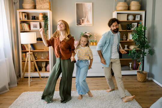 Family dancing and laughing together at home in living room