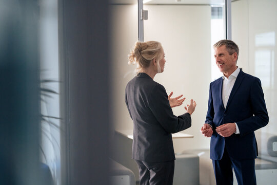 Businesswoman talking with senior colleague standing at office