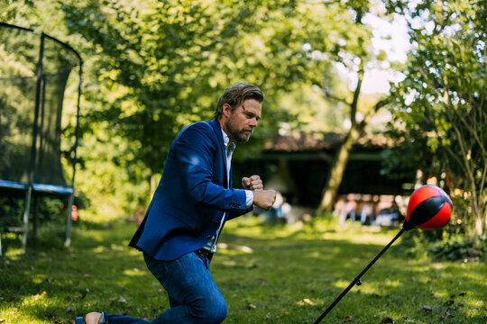 Businessman hitting punching bag at park