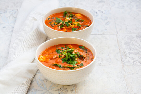 Two bowls of vegetarian halloumi korma curry with spinach and cashews