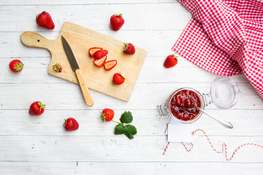 Strawberry jam in a jar with fresh strawberries and cutting board