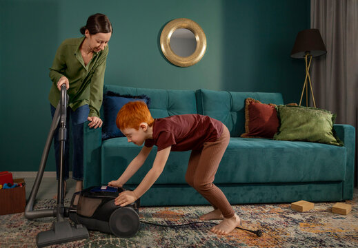 Mother and son tidying up the living room with a vacuum cleaner
