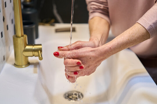 Washing hands under a running faucet in a bathroom sink