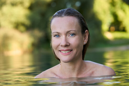 Smiling woman bathing in natural water outdoors, wellness and beauty