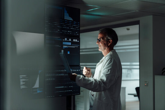 Doctor analyzing medical data on digital screens working overtime
