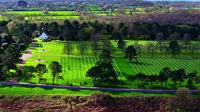 Normandy American Cemetery with rows of white crosses and a chapel in lush green landscape.