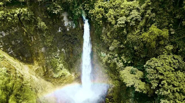 A powerful waterfall tumbling into a crystal-clear pool surrounded by vibrant, dense tropical jungle vegetation in Lake Sebu, South Cotabato, Philippines.