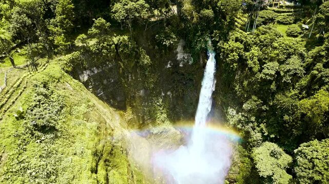 A multi-stage waterfall descending through a vibrant tropical mountain gorge in Lake Sebu, South Cotabato, Philippines, cascading into a serene pool with misty forest basin views.
