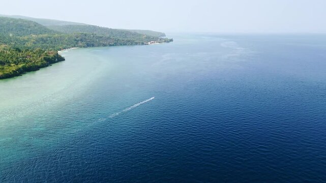 Sweeping aerial views of jungle-covered headlands overlooking calm blue water and open sea vistas along the coastline of Glan, Sarangani, Philippines.