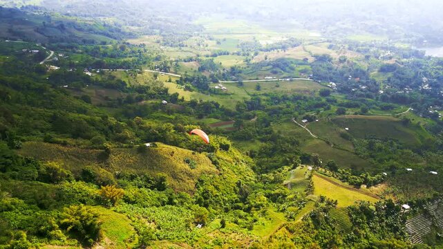 Aerial footage of paragliders and red parachutes soaring over lush green hills and valleys in Lake Sebu, South Cotabato, Philippines, showcasing outdoor adventure sports.