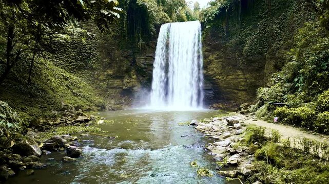 A large waterfall plunging into a still natural pool surrounded by dense tropical foliage and jungle greenery in Lake Sebu, South Cotabato, Philippines.