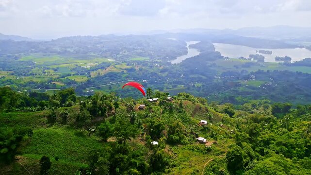 Aerial views of a red hot air balloon, parasailers, and paragliders over lush valleys, rice fields, and hillsides in Lake Sebu, South Cotabato, Philippines.