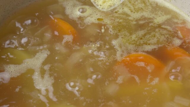 Chicken bouillon powder added into a boiling soup. Slow motion close up
