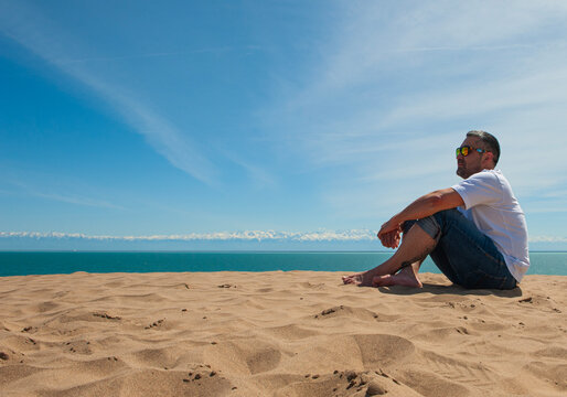 man on the beach relaxing and watching sea