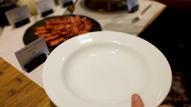 Person Placing Sliced Spanish Chorizo Sausage onto a White Plate