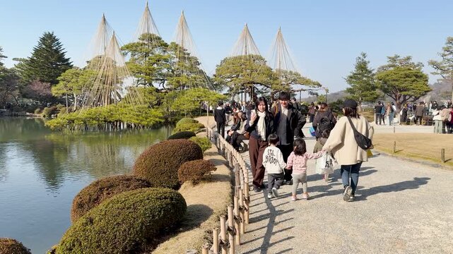 Asian Family Walking Through Kenrokuen Garden Near Lake in Kanazawa Japan
