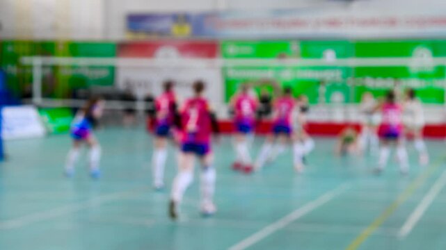 Group of teen girls playing indoor volleyball. Sport background blur.