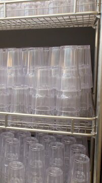 Hand Reaching for Plastic Cup from Stacked Metal Shelf in Restaurant